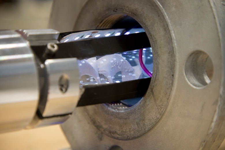 Titanium dioxide and polylactic acid filament printed ‘corkscrews’ rest in a quartz tube surrounded by UV light after running a test at the Environmental Laboratory, July 17.