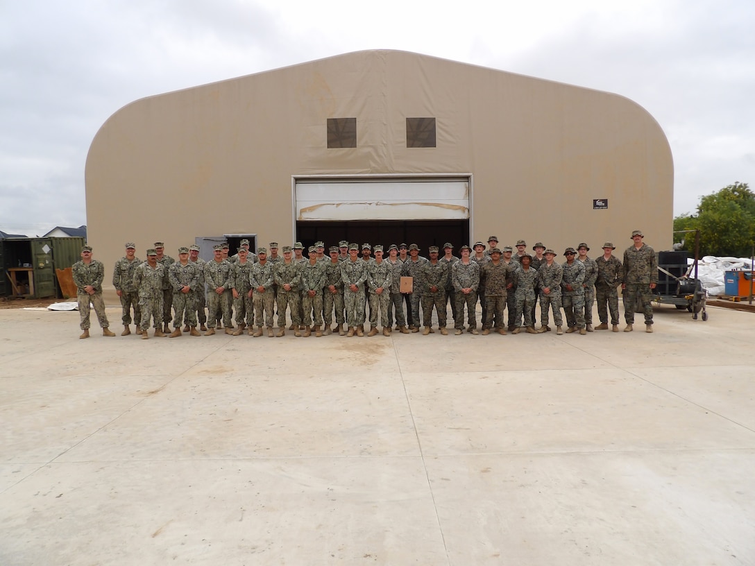 U.S. Marines with the Hershel “Woody” Williams (HWW) Marine Detachment, and Sailors with Naval Mobile Construction Battalion 11, pose for a photo in front of a constructed boat storage facility in Accra, Ghana, in July 2024.