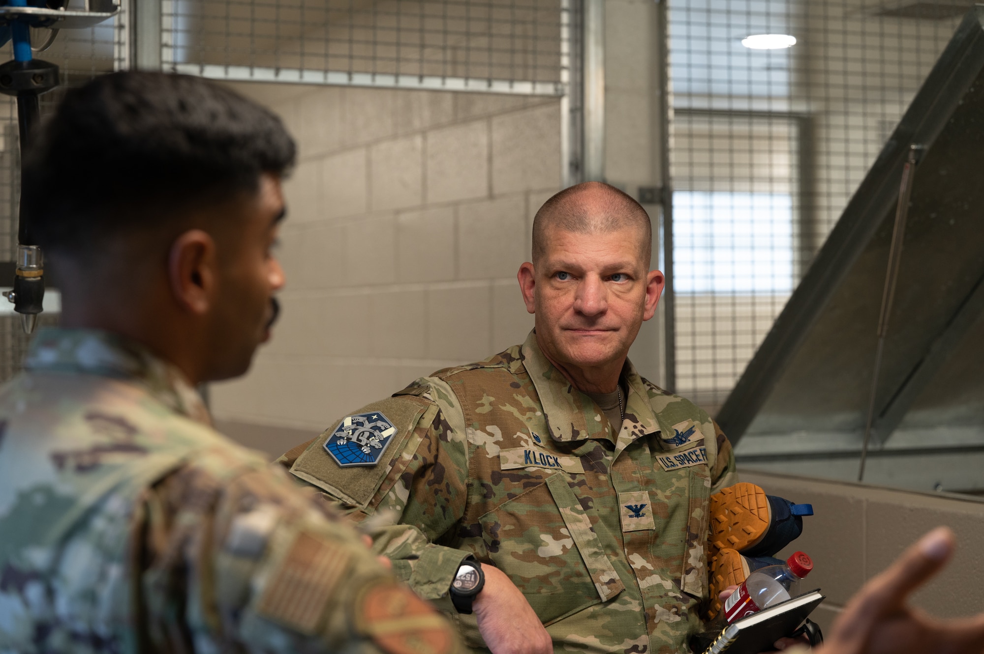 U.S. Air Force Staff Sgt. Ivan Mendez, 21st Security Forces Squadron military working dog trainer and U.S. Space Force Col. Kenneth Klock, Space Base Delta 1 commander, discuss the kennel operations and how they are used to house and train the military working dogs.