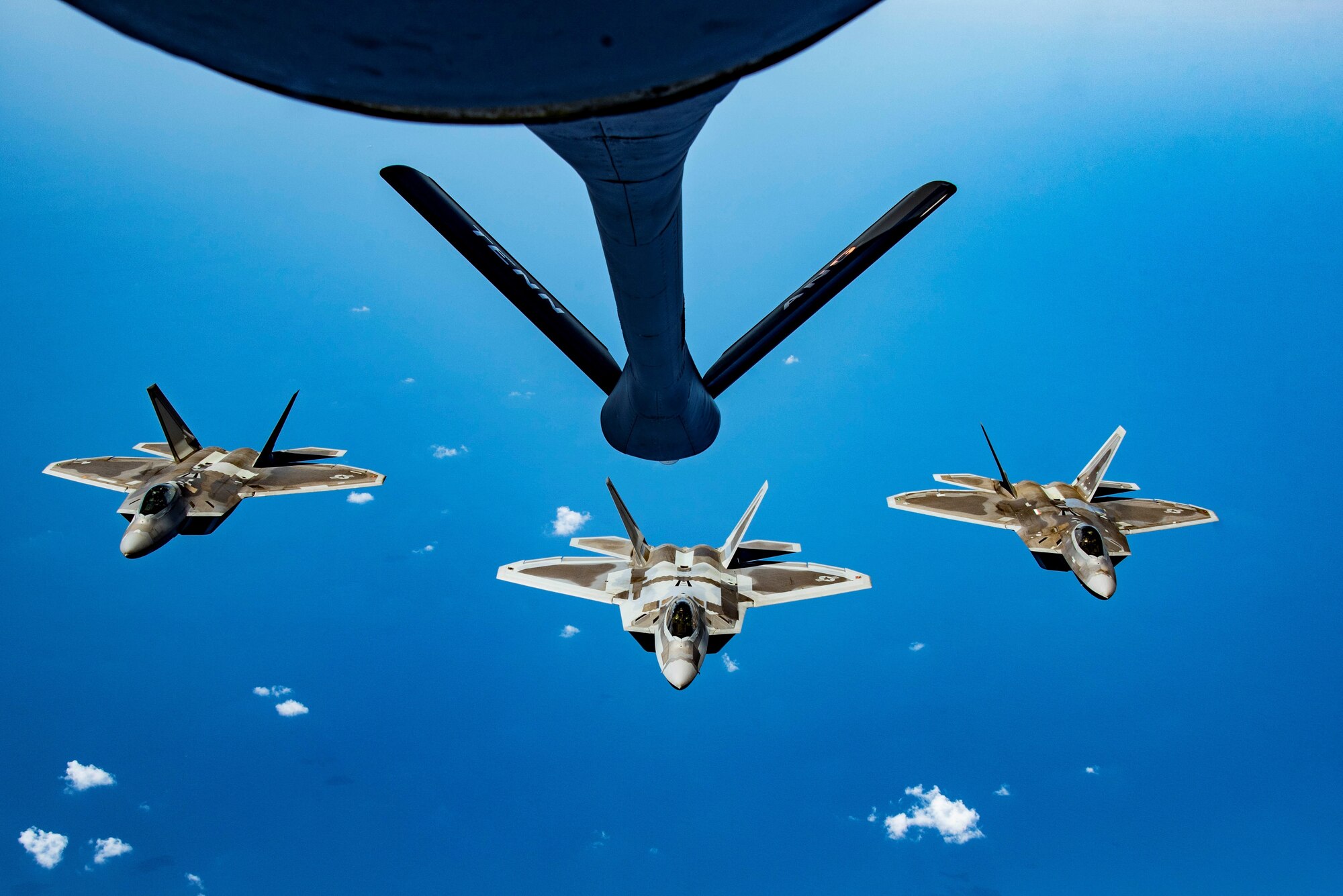 KC-135 about to aerial refuel three F-22s.