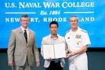 A man is presented an award from two leaders at the U.S. Naval War College.