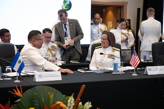 Military personnel talk while sitting at a table.