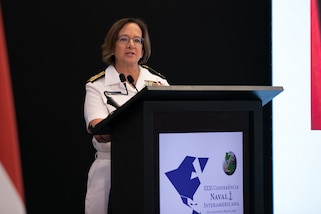 A female military officer speaks from a podium.