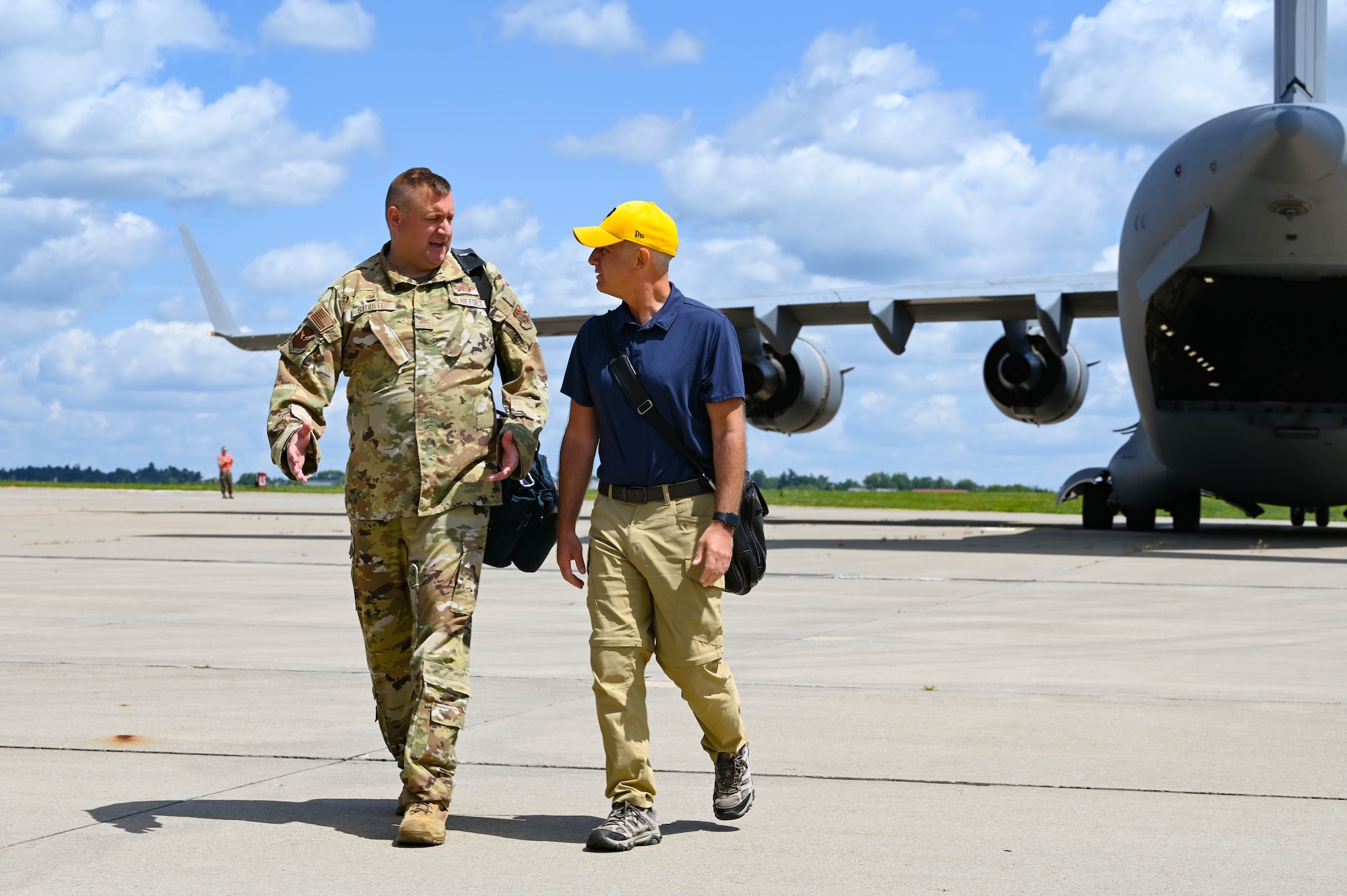 Col. Douglas Stouffer, commander of the 911th Airlift Wing, speaks with Pennsylvania State Representative Dan Miller as they walk toward camera with a C-17 Globemaster III in the background