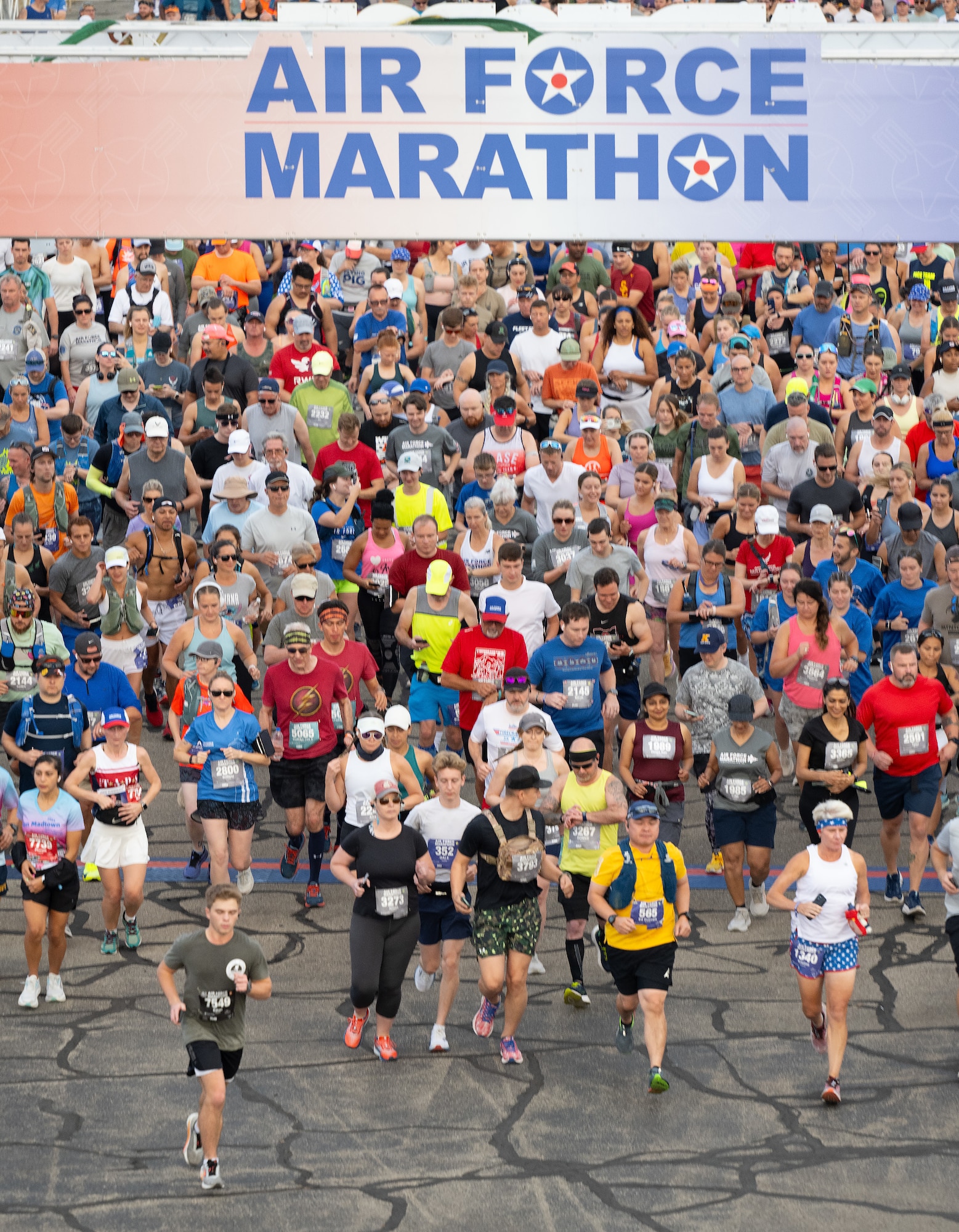 A high-angle photo of a large group of runners underneath a sign that reads "Air Force Marathon".