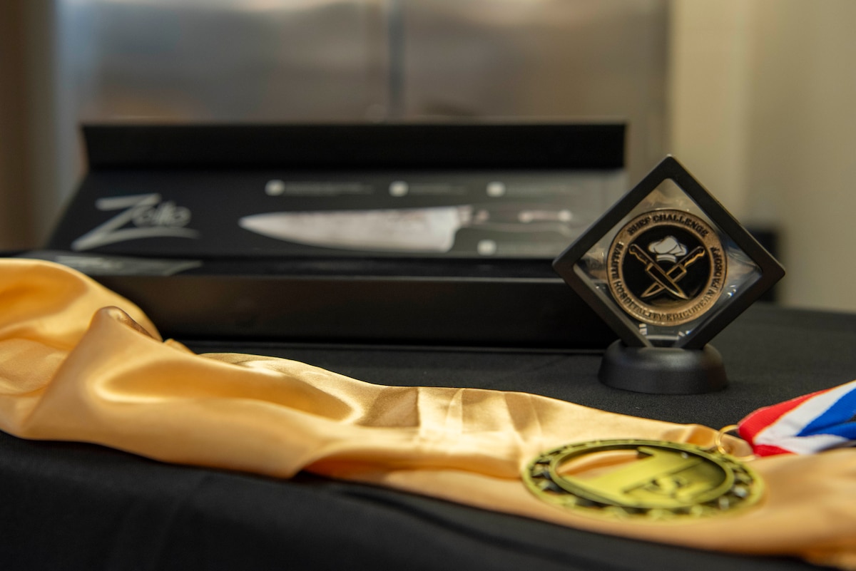 from foreground, medal, coin in holder and knife in case