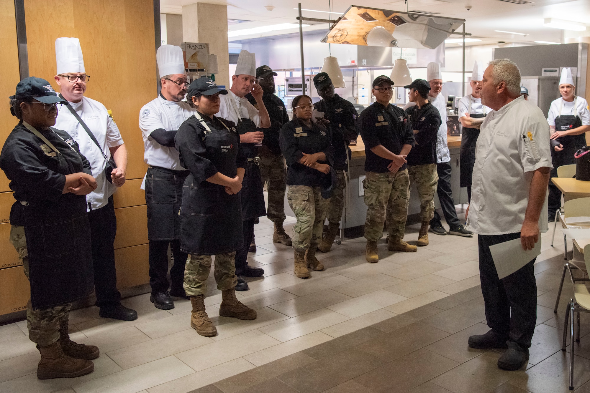 chef, at right, talks to all competitors and their chef mentors, at left, at the entrance to the kitchen