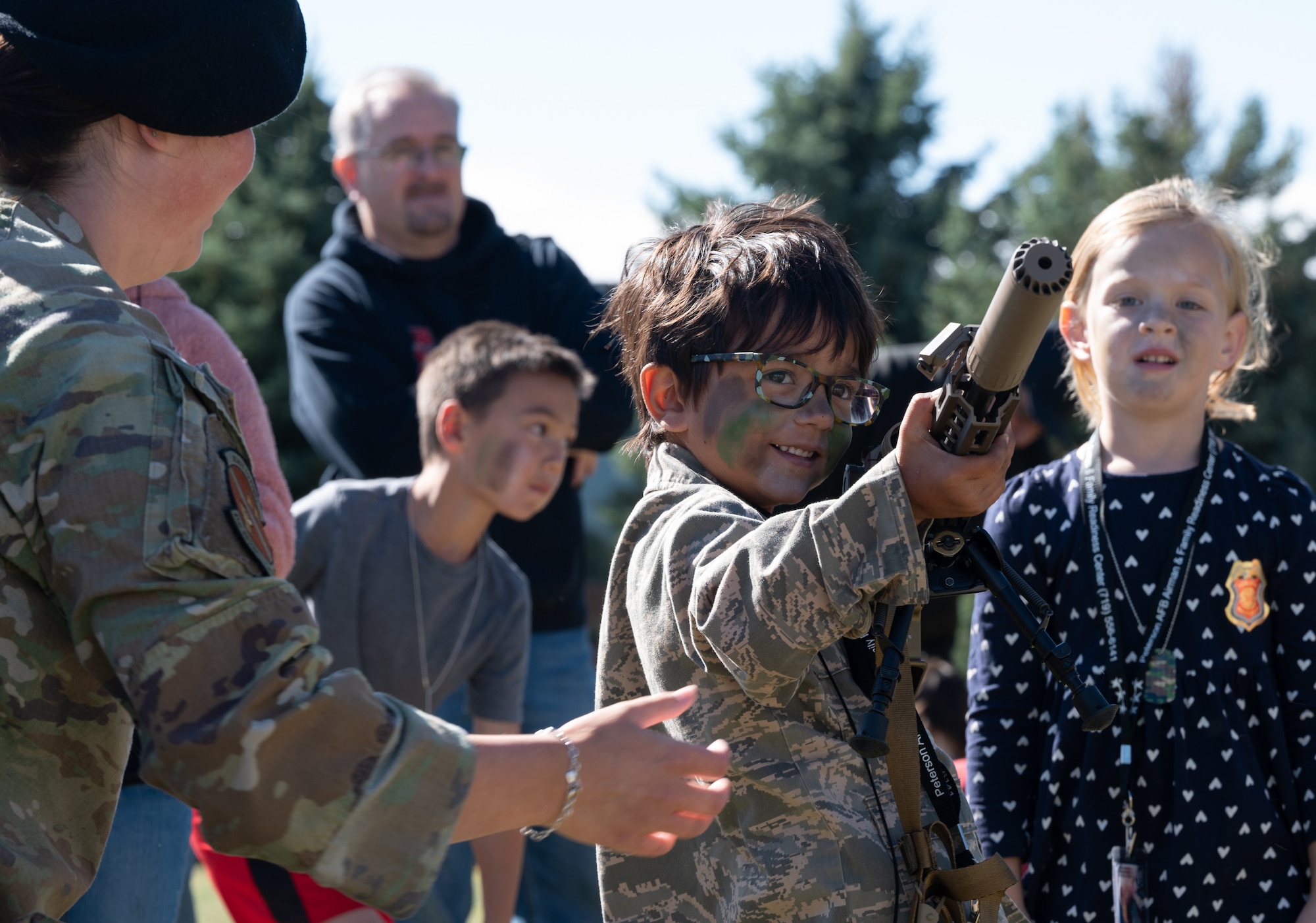 A member of the 21st Security Forces Squadron talks about the M4 carbine that a child is holding.