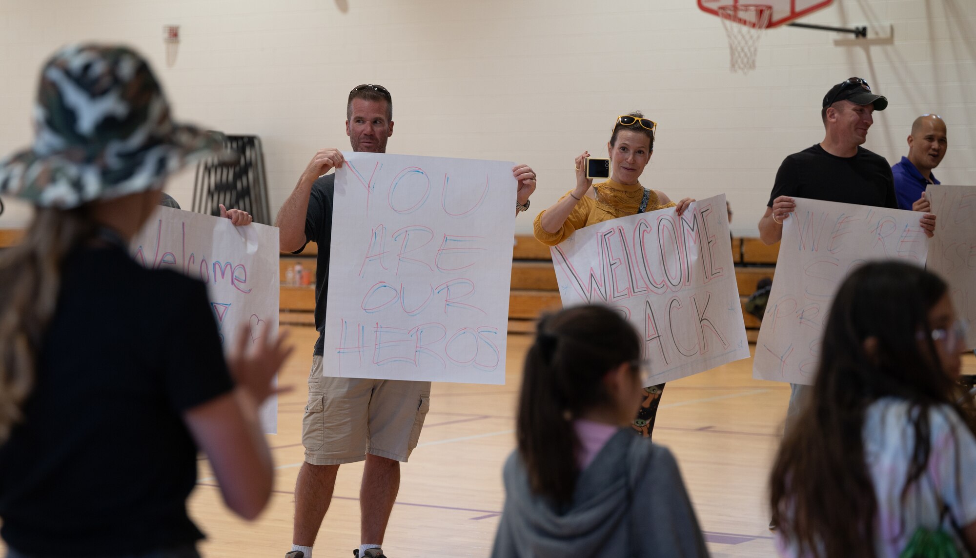 Parents welcome their kids back from their "deployment," while holding welcome back signs.