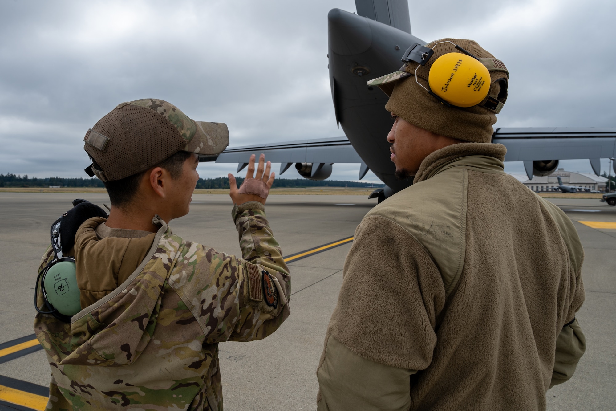 Two U.S. Air Force aircraft maintenance Airmen conduct inspection training behind a C-17 Globemaster III at Joint Base Lewis-McChord, Washington, Sept. 18, 2024.