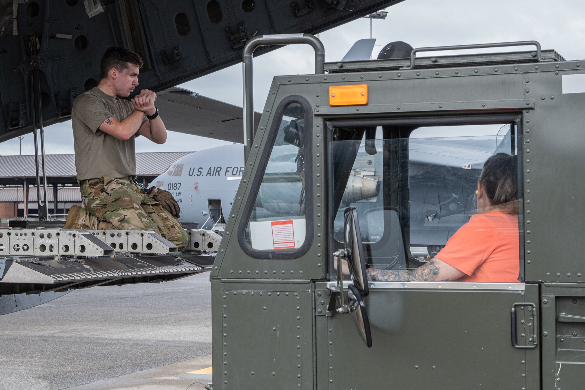 U.S. Air Force Senior Airman Brian Austin, 8th Airlift Squadron loadmaster, guides an aerial port squadron vehicle toward a C-17 Globemaster III at Joint Base Lewis-McChord, Washington, Aug. 30, 2024.