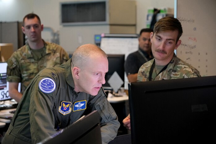 uniformed military members stand in a semicircle while one member speaks
