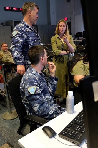 Royal Australian Air Force and U.S. civilian talk on operations floor