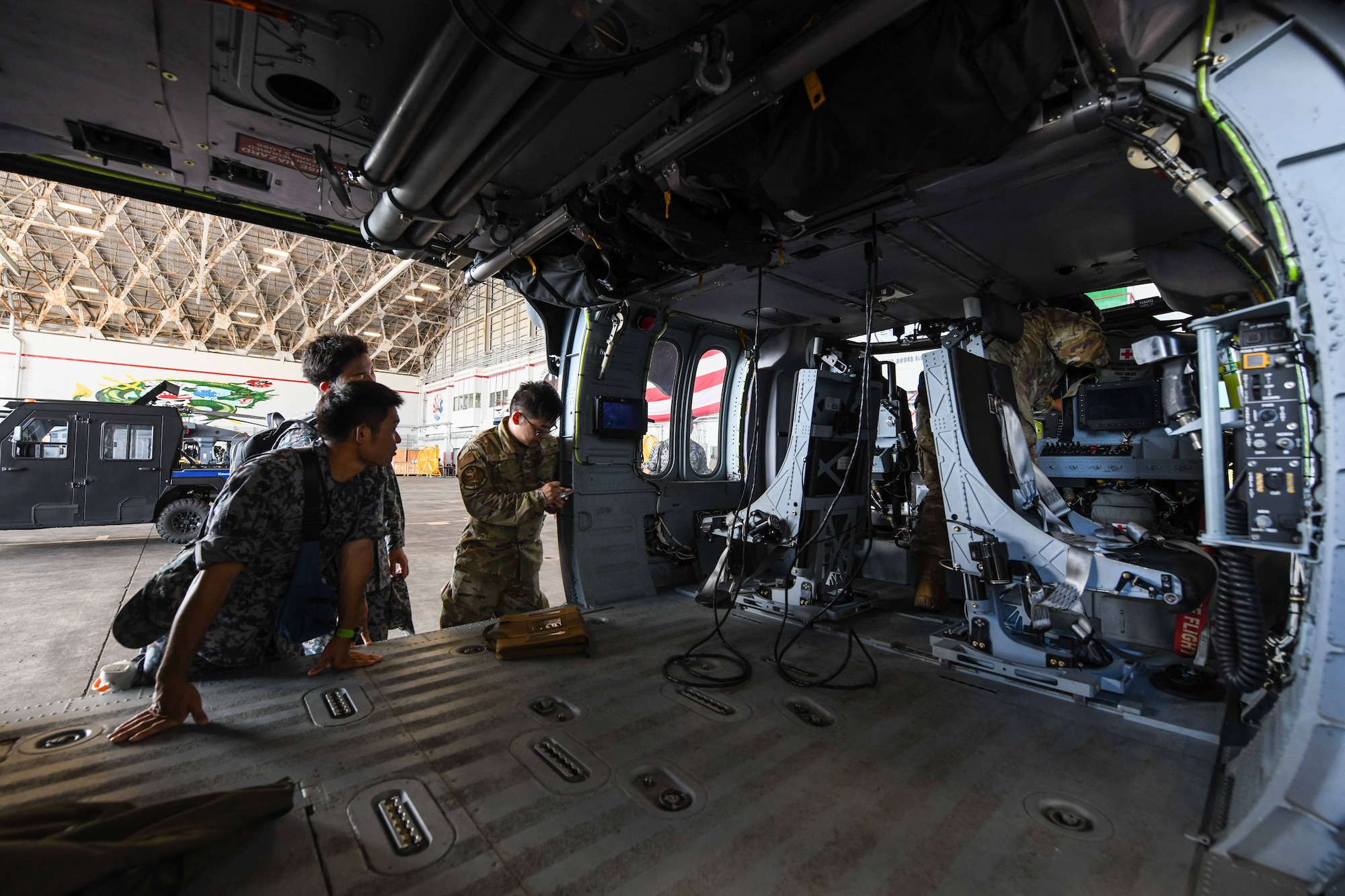 Japan Air Self-Defense Force airmen assigned to the Naha Air Rescue Squadron survey an HH-60W Jolly Green II assigned to the 33rd Rescue Squadron during a base tour hosted by the 18th Maintenance Group at Kadena Air Base, Japan, Sept. 12, 2024. The U.S. Air Force is currently phasing out the HH-60G Pave Hawk in favor of the HH-60W, an aircraft equipped with an enhanced avionics package and superior equipment. (U.S. Air Force photo by Airman 1st Class Jonathan R. Sifuentes)