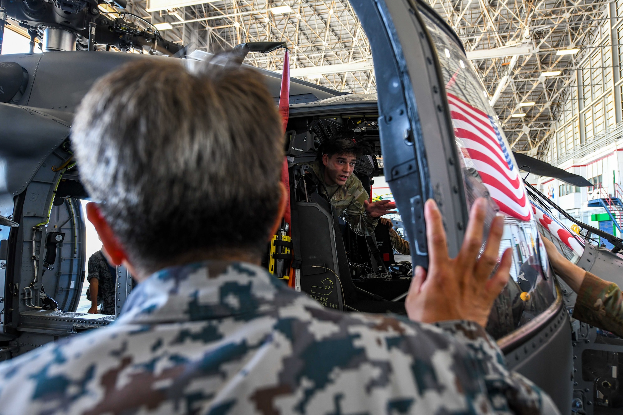 U.S. Air Force Airman 1st Class Isaiah Clemens, 33rd Rescue Squadron avionics technician, discusses HH-60W Jolly Green II capabilities during a Japan Air Self-Defense visit hosted by the 18th Maintenance Group at Kadena Air Base, Japan, Sept. 12, 2024. Showcasing operational capabilities with allied forces provides knowledge that service members can apply to their daily operations, strengthening interoperability for real world operations or emergencies. (U.S. Air Force photo by Airman 1st Class Jonathan R. Sifuentes)
