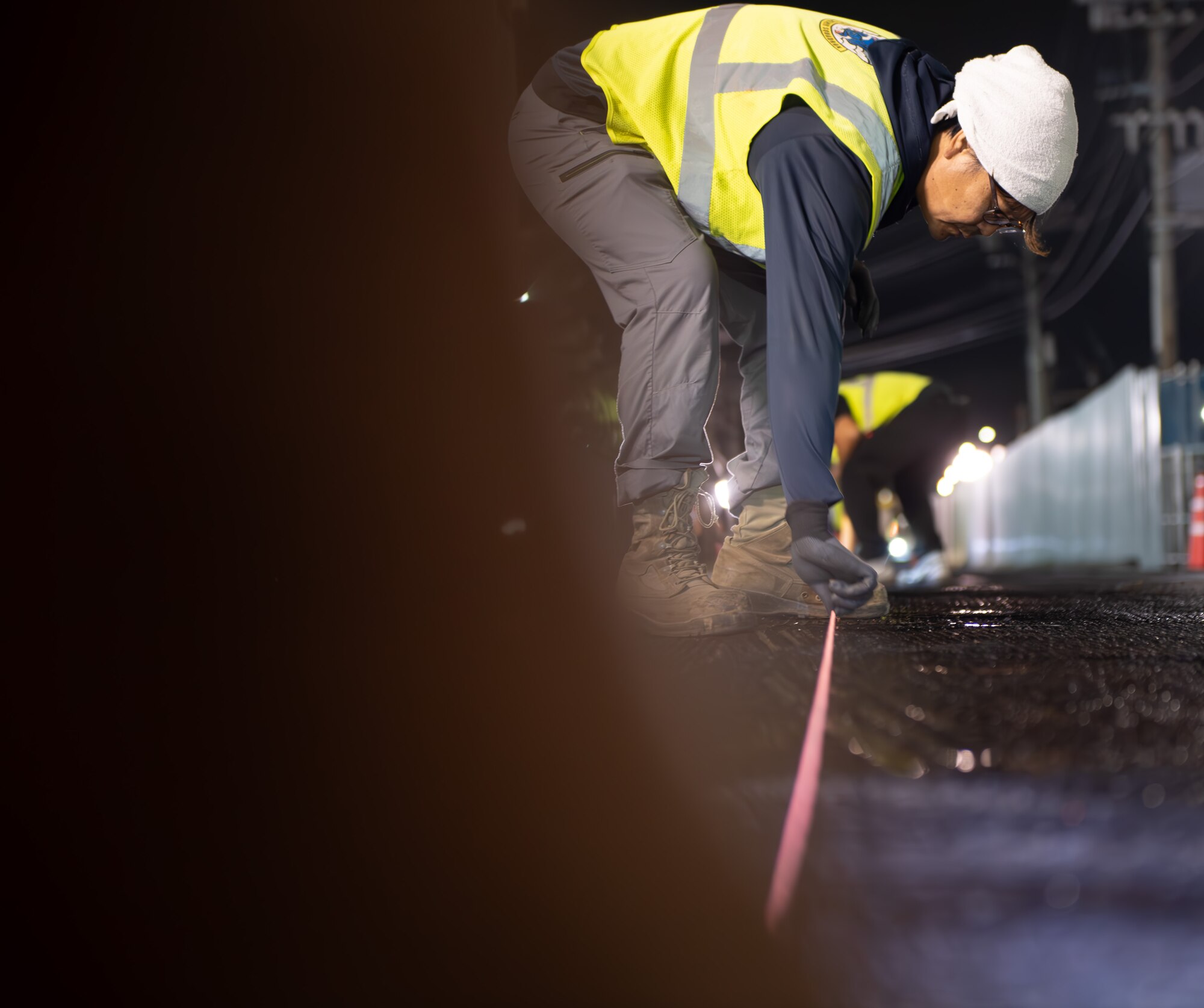A CES member uses a measuring tape on the road about to be paved.