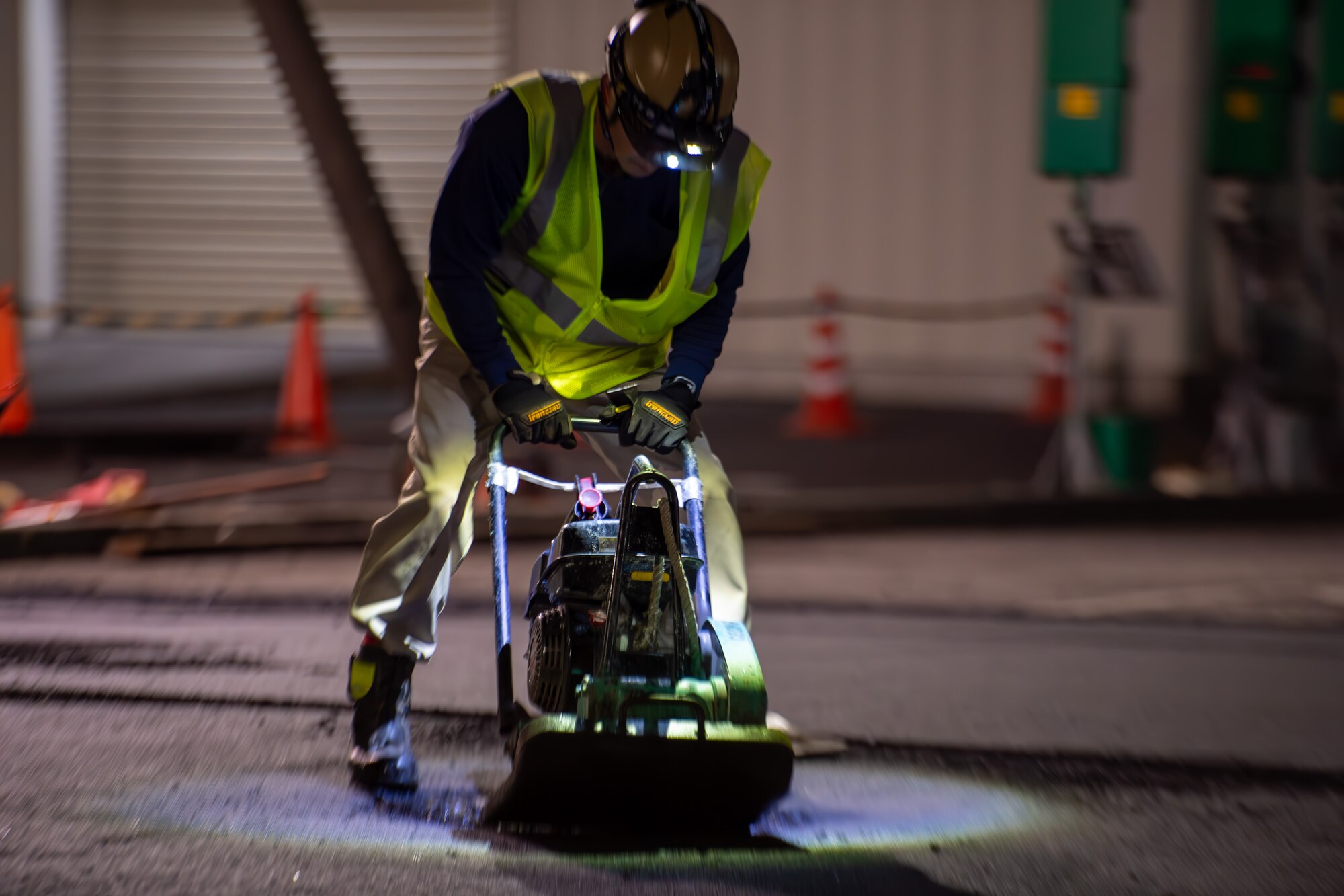 A CES member uses equipment to pack down freshly laid asphalt.