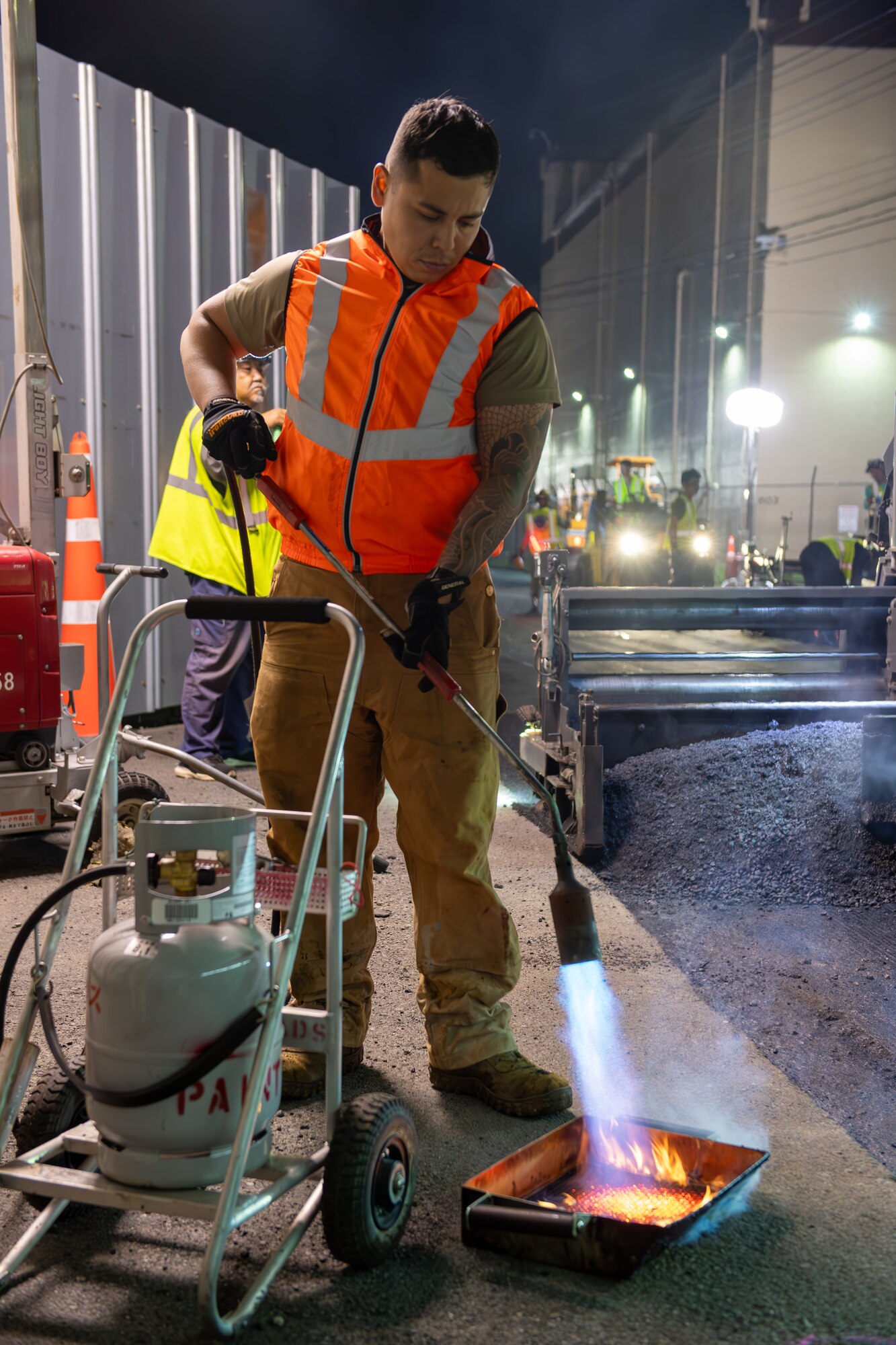 A CES member uses heats a piece of equipment used in paving the street.