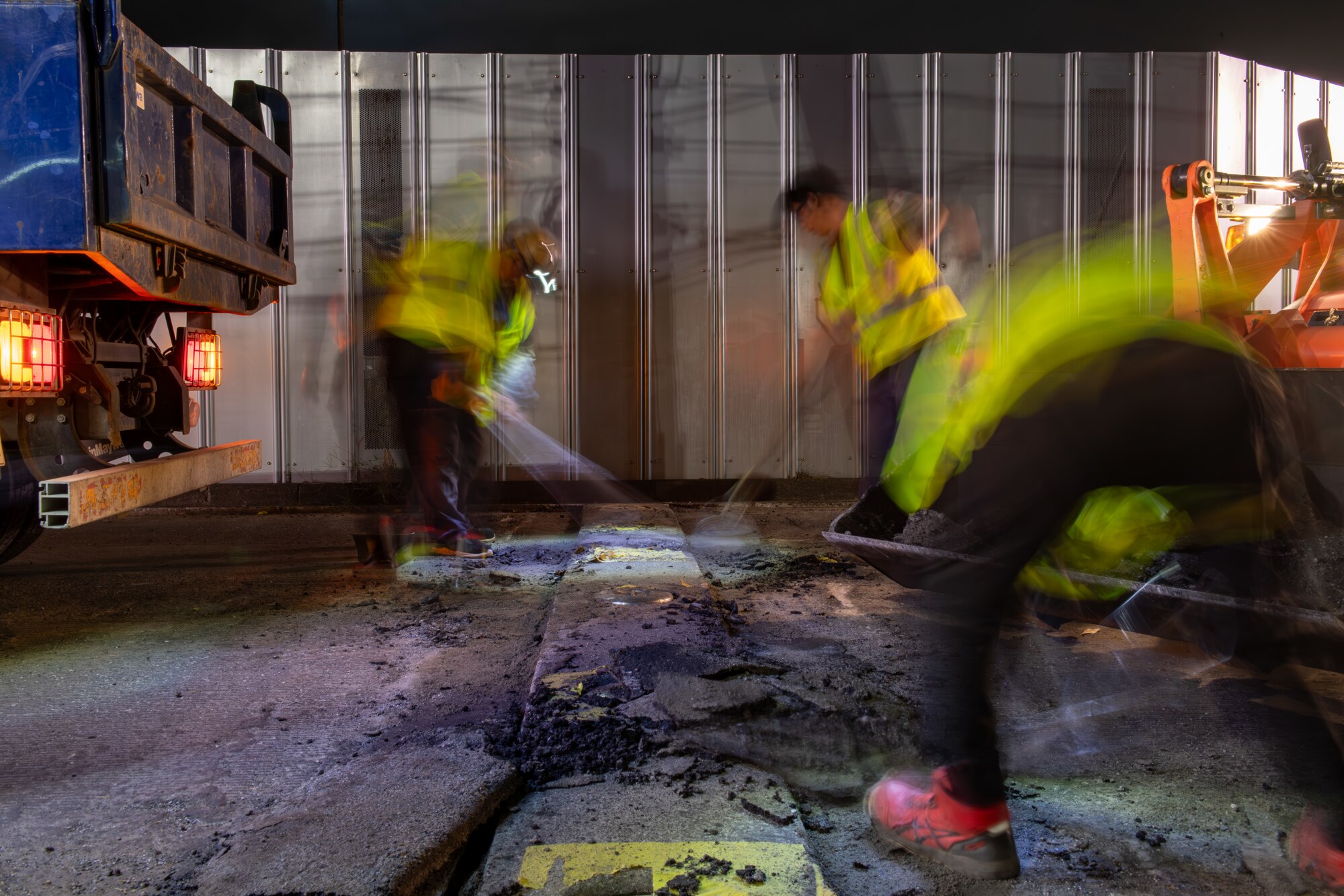 Workers clear the street of any loose rubble before laying asphalt.