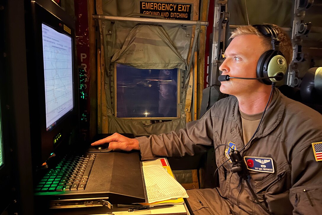 An airman tracks a storm on a computer aboard an aircraft.