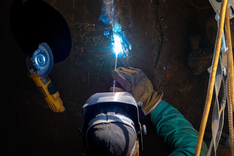 A welder repairs a piece of metal.