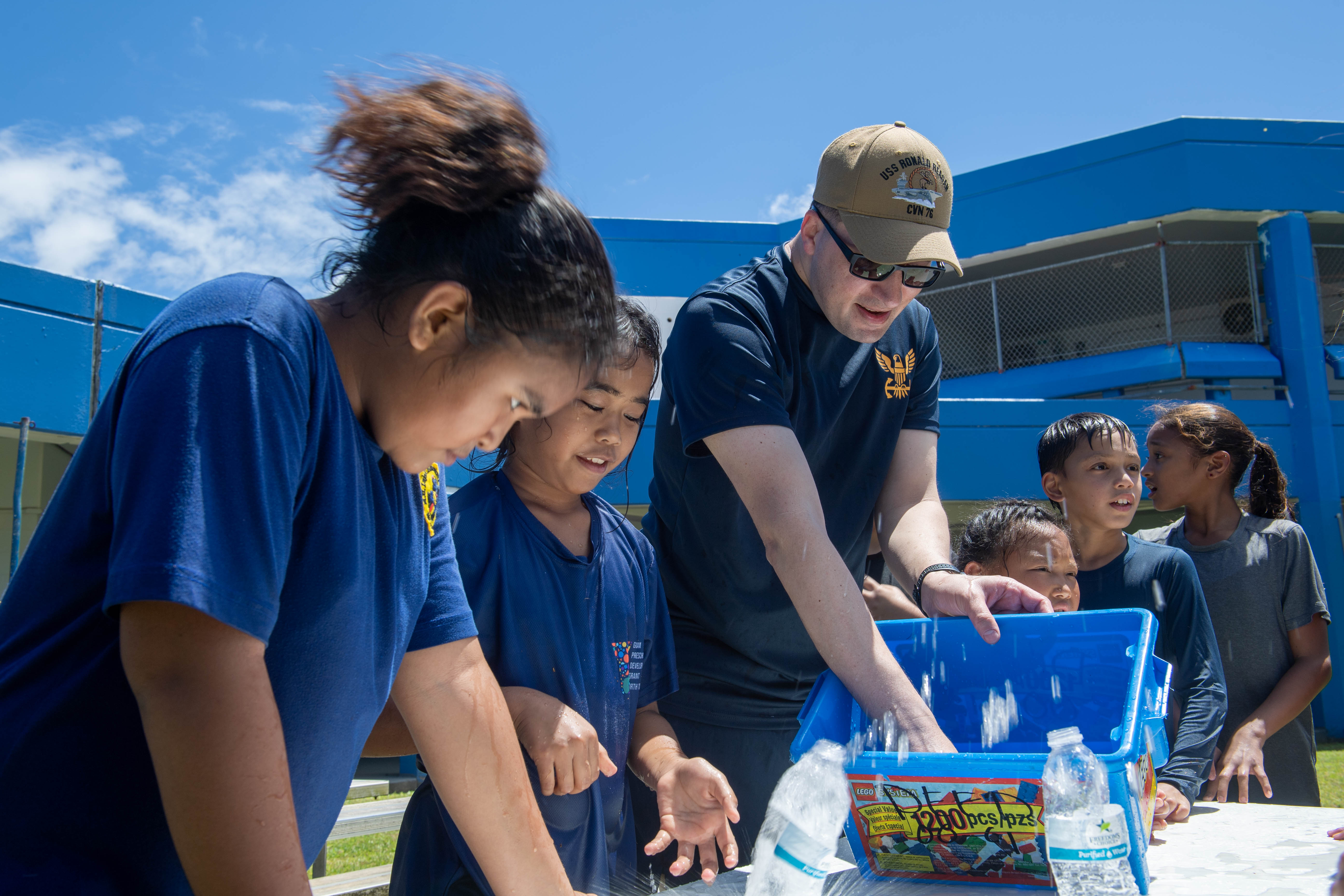 Chief Religious Program Specialist Angelo Martinez, from Fajardo, Puerto Rico, assigned to the U.S. Navy’s only forward-deployed aircraft carrier, USS Ronald Reagan (CVN 76), participates in water activities with Manuel Ulloa Lujan Elementary School students in the yard of the school during a community relations event, June 20. Ronald Reagan, the flagship of Carrier Strike Group 5, provides a combat-ready force that protects and defends the United States, and supports alliances, partnerships and collective maritime interests in the Indo-Pacific region.