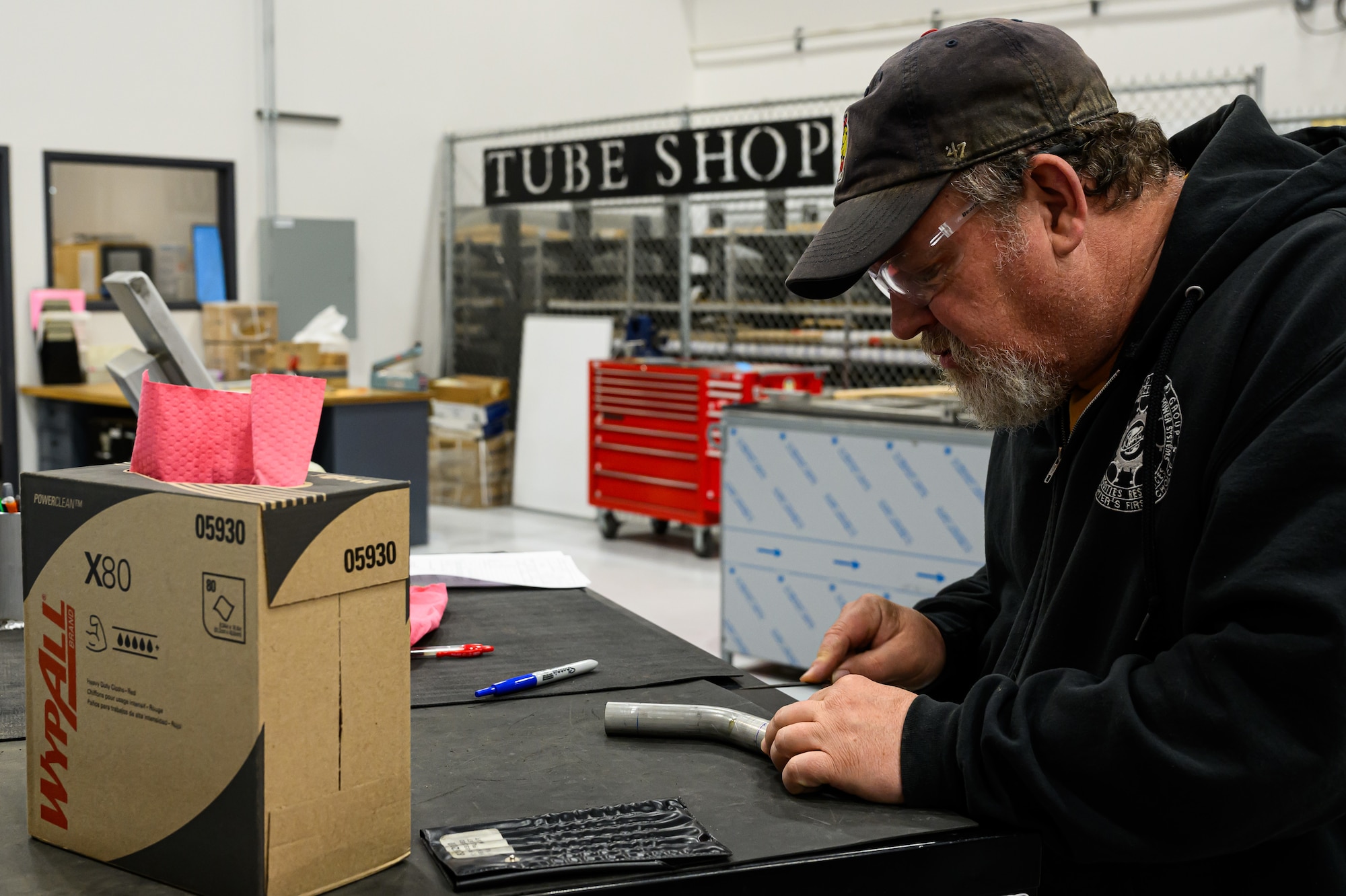 A worker uses a measuring device on a piece of pipe tubing.