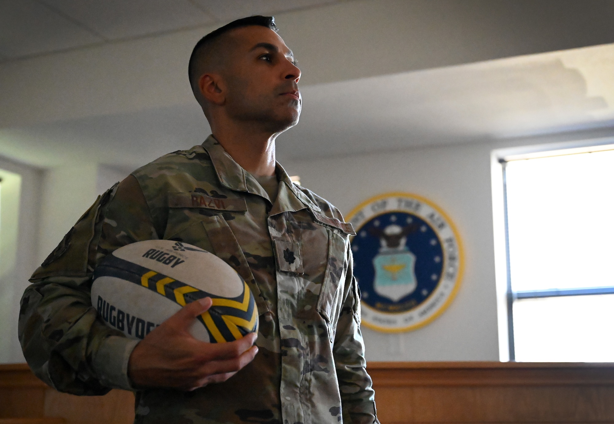 Lt. Col. Saleem Razvi, 7th Bomb Wing Legal Office staff judge advocate, poses for a photo with his rugby ball in the courtroom at Dyess Air Force Base, Texas, Sept. 27, 2024. Razvi, who has played rugby since he was in college, recently led the U.S. Air Force Men’s Rugby Team to a second-place finish in the Armed Forces tournament in Colorado. During his first year as head coach, he led his team to score more than 20 points during the tournament and had two players selected to the All-Armed Forces team. (U.S. Air Force photo by Staff Sgt. Holly Cook)