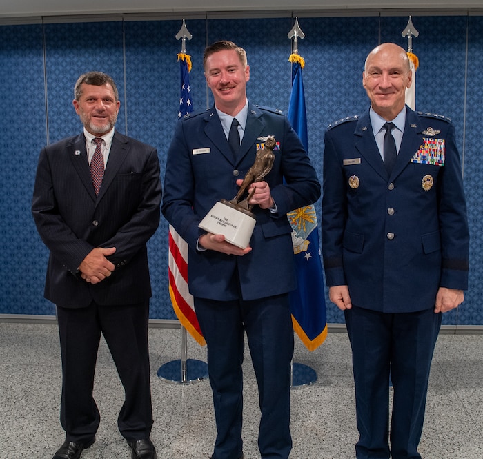 Capt. Harry “Butcher” McMahon holds the 2024 Kolligian Trophy, flanked by Air Force Chief of Staff Gen. David Allvin and Mr. Kyle Anderson, at the Pentagon, Arlington, Va., Sept. 26, 2024. The Koren Kolligian Jr. Trophy recognizes outstanding feats of airmanship by aircrew members who by extraordinary skill, exceptional alertness, ingenuity, or proficiency, averted accidents or minimized the seriousness of the accidents in terms of injury, loss of life, aircraft damage or property damage. (U.S. Air Force photo)