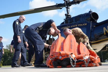 Chief Warrant Officer 5 Dino Parmentier, state standardization officer, Headquarters and Headquarters Company, 204th Theater Airfield Operations Group, inspects a water bucket with Louisiana State Police members during an aerial firefighting training exercise at the Joint Emergency Services Training Center in Zachary, La., Sept. 25, 2024.