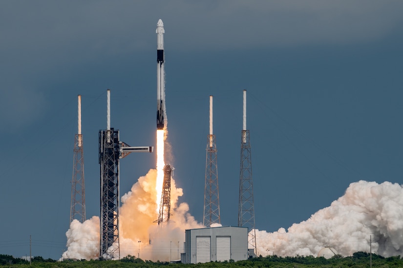 A rocket leaves behind flames and smoke as it launches with two towers on either side.