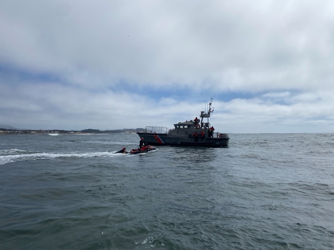 A Coast Guard 47-foot Motor Lifeboat (MLB) and its crew is seen assisting a boater off a San Francisco Fire Department jetski onto the MLB.