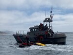 A Coast Guard 47-foot Motor Lifeboat (MLB) and its crew is seen assisting a boater off a San Francisco Fire Department jetski onto the MLB.