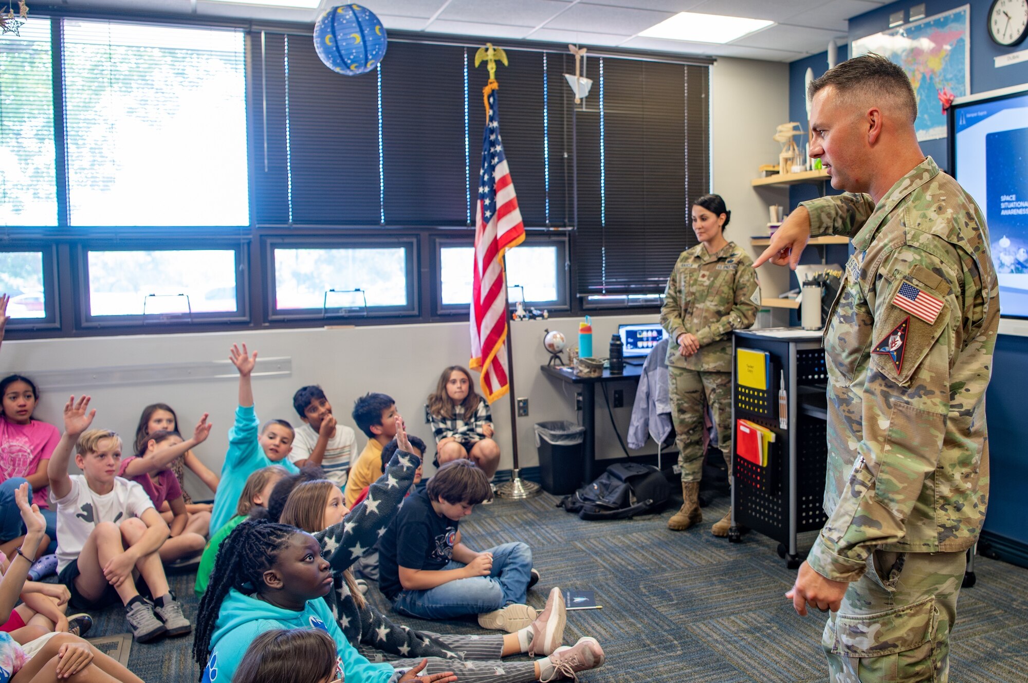 Two military members in uniform speak to group of fifth grade students