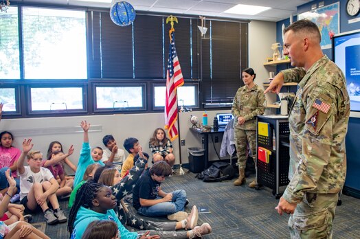  Two military members in uniform speak to group of fifth grade students