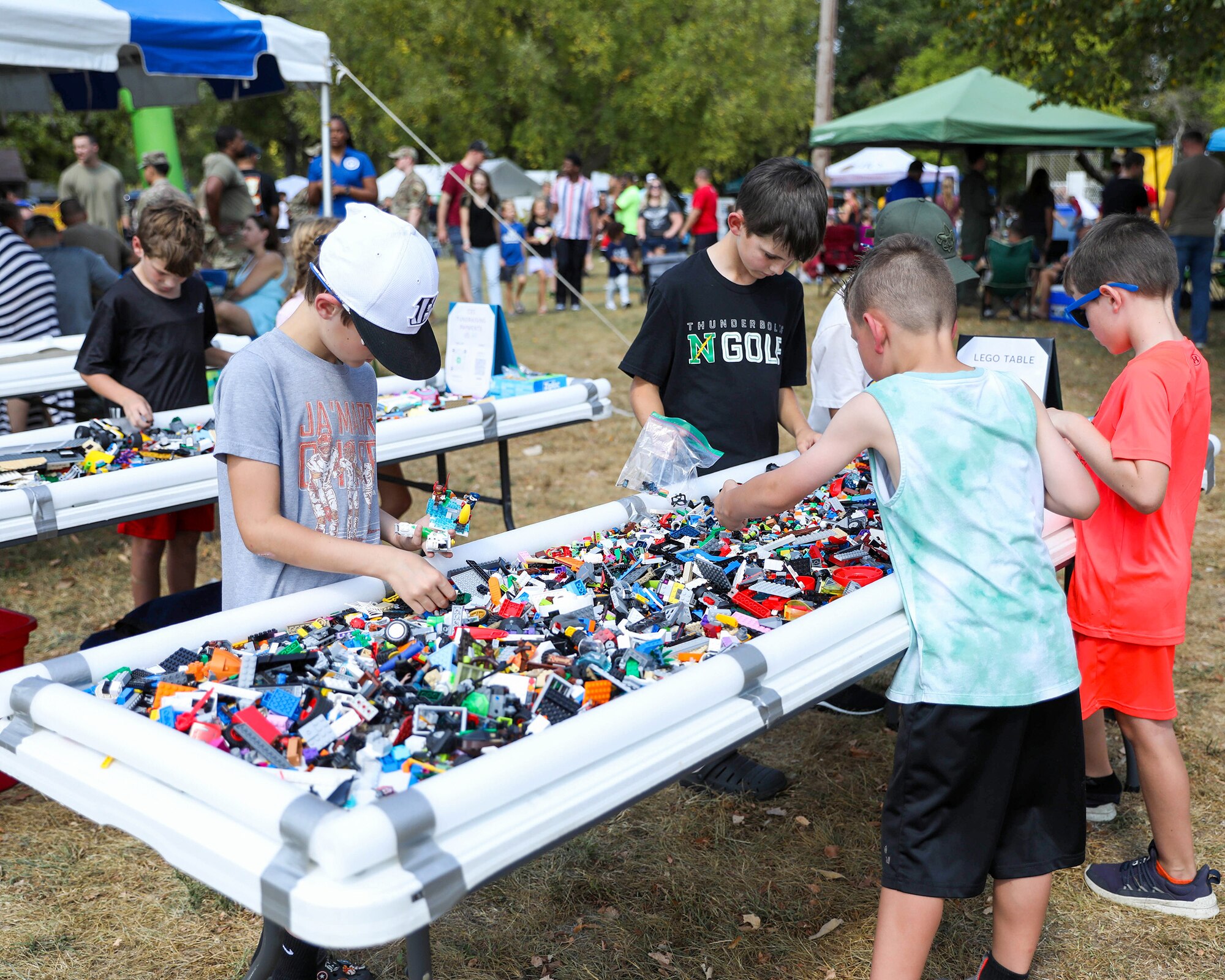 Children enjoy picking out LEGOs at the LEGO table during the 445th Airlift Wing's annual family day tailgate event at Bass Lake on Wright-Patterson Air Force Base, Ohio, Sept. 14, 2024. 
Participants enjoyed corn hole, children’s bouncy houses, dunk tank, flag football, face painting and other activities. A C-17 Globemaster III static display was available for tours and a DJ was on hand for entertainment. In addition, various helping agencies provided useful information to Airmen and their families. The base USO provided a kids zone for the event.