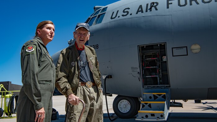 Two people stand next to a C-130 aircraft.
