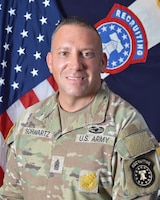 Male Soldier in front of United States and Army Recruiting Brigade flags