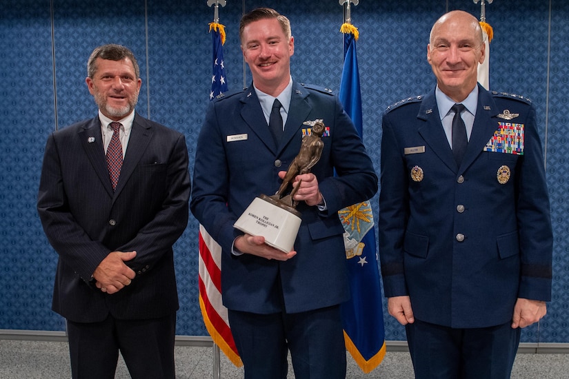 An airman holds a trophy while posing for a photo.