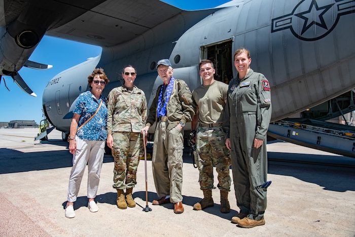 A group of five people stand in front of a C-130 aircraft side-by-side.