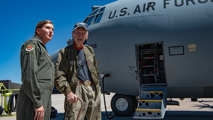 Two people stand next to a C-130 aircraft.