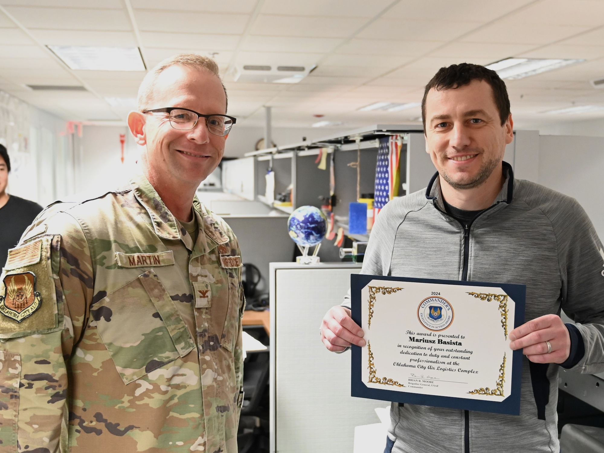 Two men hold an award certificate.
