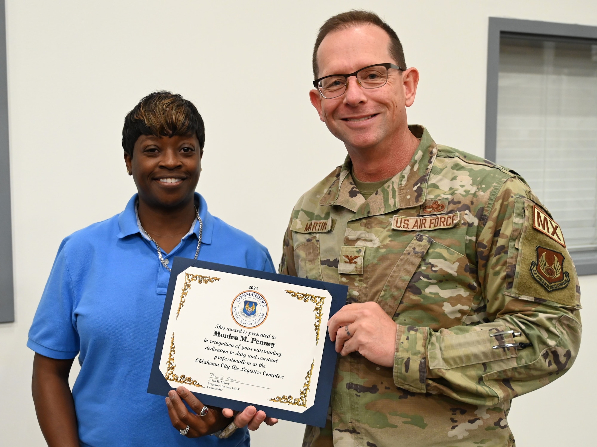 A woman and man hold an award certificate.
