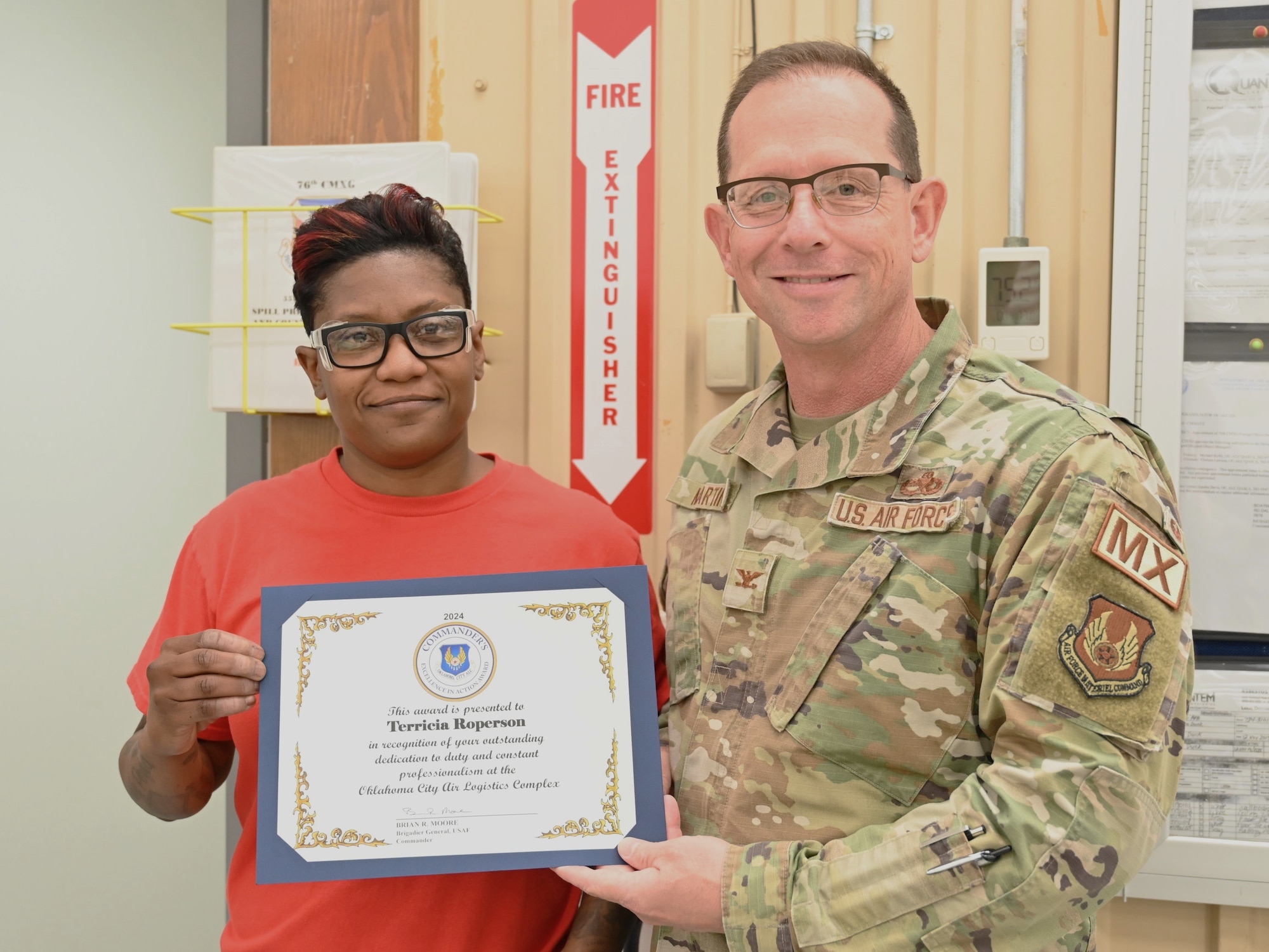 A woman and man hold an award certificate.