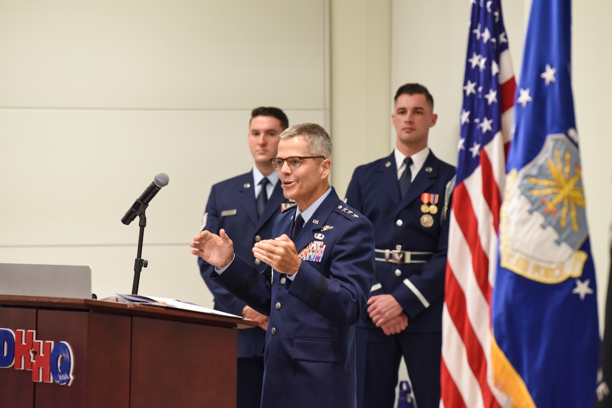 Image of an Airman speaking at a podium.