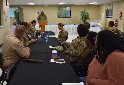 Army Chaplain with his head bowed stands behind a podium and says a prayer before breakfast.