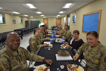 Soldiers in Army uniform and Army Civilian employees have a conversation over a pancake breakfast