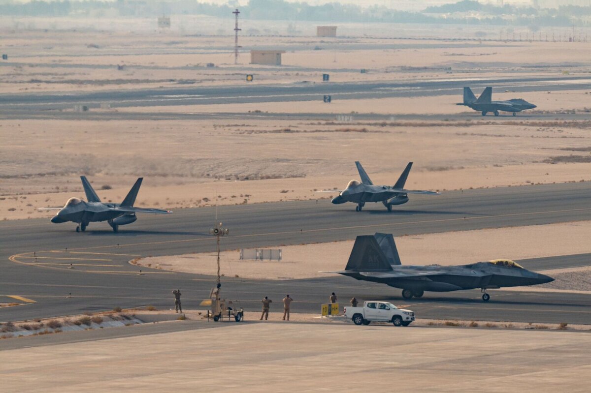 Four military jets are at various positions on a desert runway.