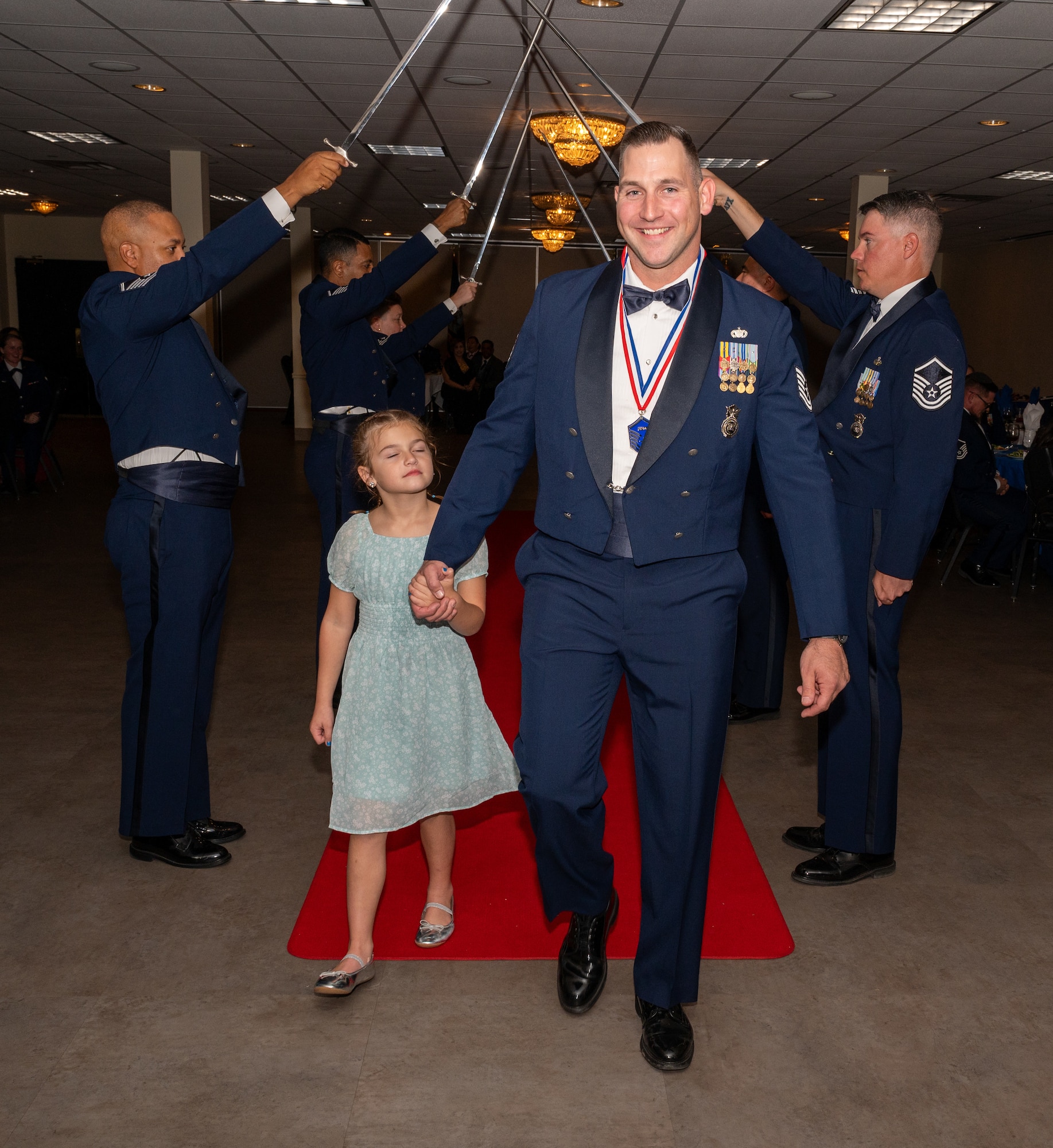 U.S. Air Force (M)Sgt Willian Slifer, 47th Security Forces Squadron, walks under the Saber Team's swords during the senior non-commissioned officer induction ceremony at Laughlin Air Force Base, Texas, Sept. 27, 2024. The induction ceremony brings Airmen together to celebrate the achievement of entering the realm of senior enlisted leaders. (U.S. Air Force photo by Staff Sgt. Nicholas Larsen)