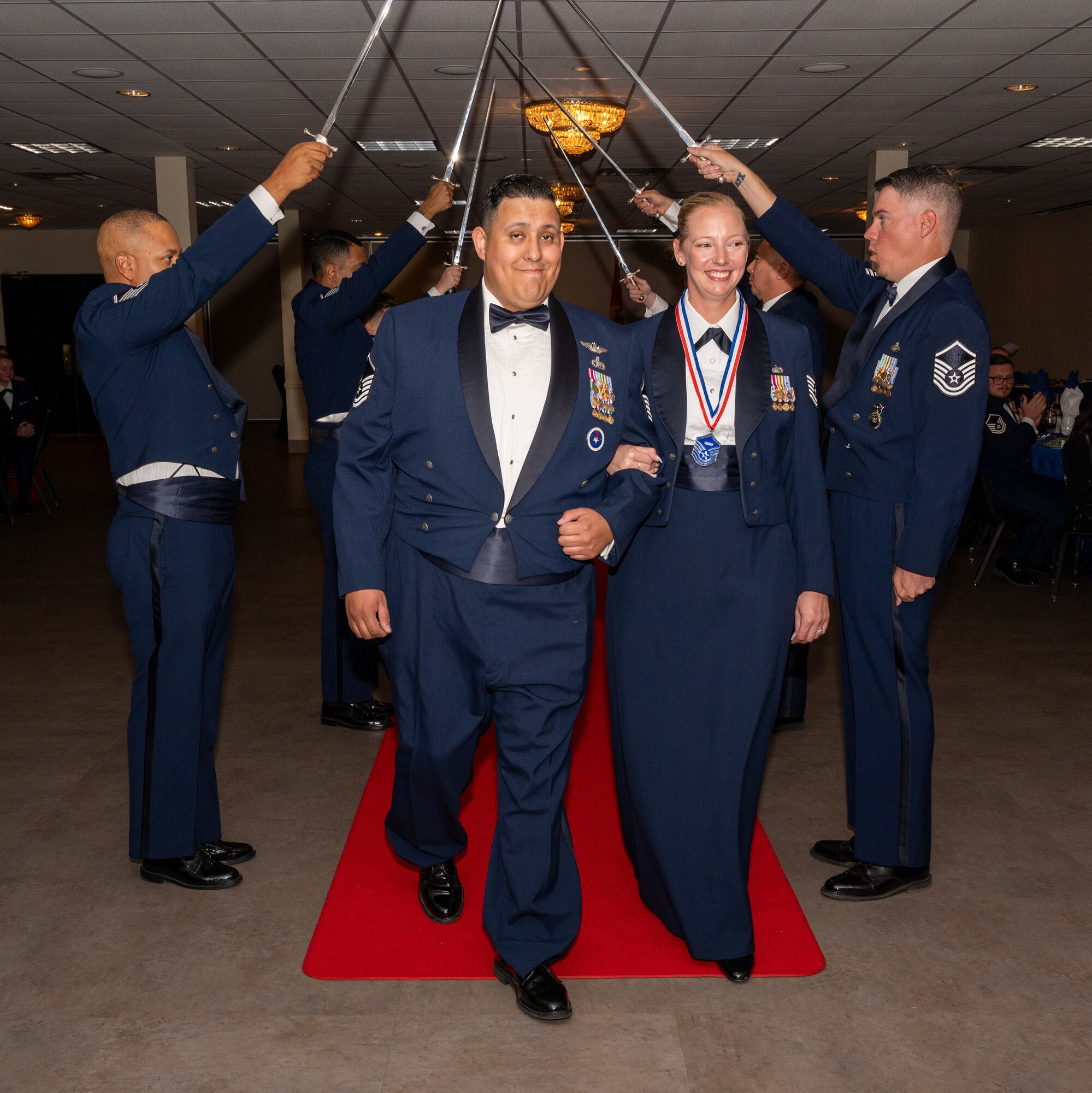 U.S. Air Force (M)Sgt Rebecca Pelayo-Reles, 47th Contracting Squadron, walks under the Saber Team's swords during the senior non-commissioned officer induction ceremony at Laughlin Air Force Base, Texas, Sept. 27, 2024. The induction ceremony brings Airmen together to celebrate the achievement of entering the realm of senior enlisted leaders. (U.S. Air Force photo by Staff Sgt. Nicholas Larsen)